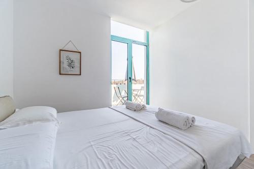una camera da letto bianca con un grande letto con asciugamani sopra di Santorini Wave Loft 2 a Gjilek