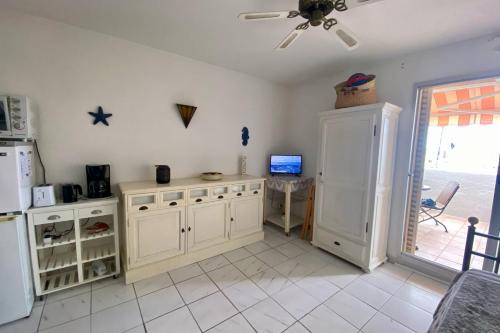 - une cuisine avec des placards blancs, une table et un réfrigérateur dans l'établissement Apartment of 26 m2 with view on the boats, à Gruissan