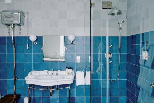 a blue tiled bathroom with a sink and a shower at Artist Residence London in London