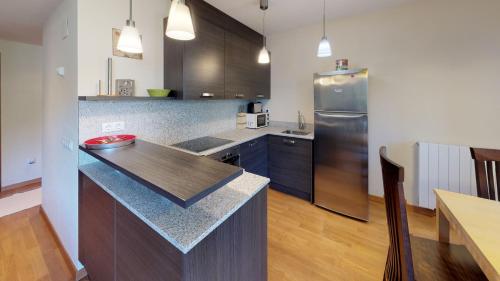 a kitchen with a counter and a stainless steel refrigerator at Los Altos de Escarrilla - tucasaenlospirineos in Escarrilla