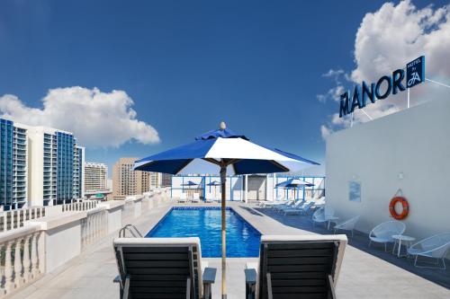 a pool with chairs and an umbrella on a balcony at JA The Manor Hotel, Dubai in Dubai