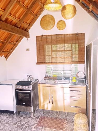 a kitchen with a stove and a sink at Chalé Rosa Chalezinho da Serra in Natividade da Serra