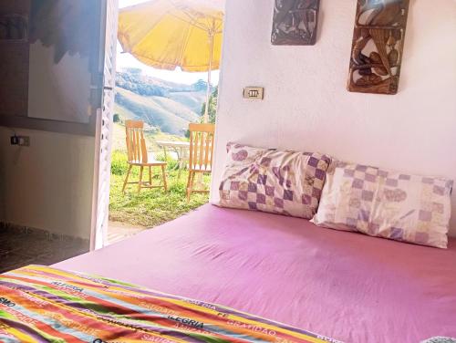 a bedroom with a bed and an open door with an umbrella at Chalé Rosa Chalezinho da Serra in Natividade da Serra