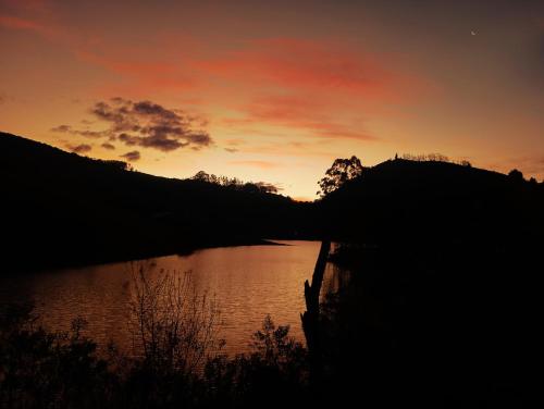 a sunset over a lake in front of a hill at Chalé Rosa Chalezinho da Serra in Natividade da Serra