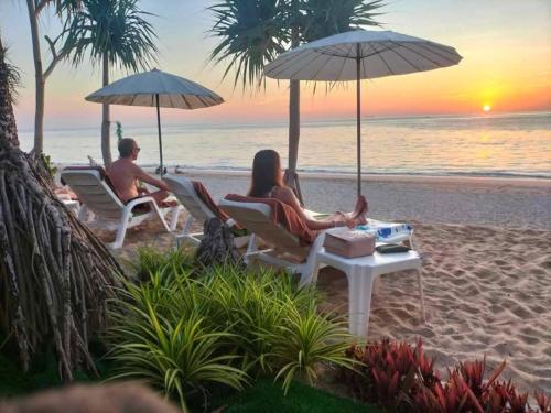 two people sitting on the beach under umbrellas at Beach Home Lanta in Ko Lanta