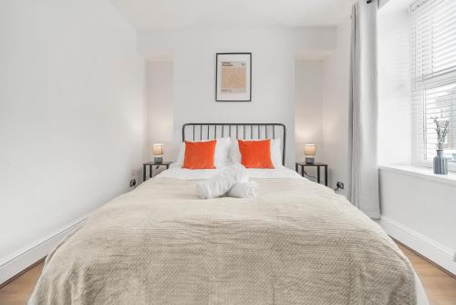 a white bedroom with a large bed with orange pillows at The Modern Cwtch House - Swansea in Gorseinon