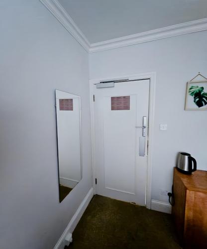a white room with a door and a mirror at The Coach House in Otterburn