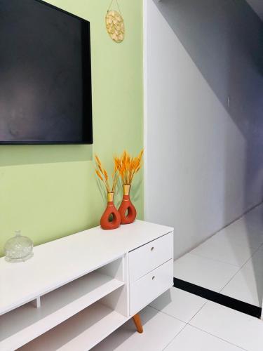 a white entertainment center with vases and a flat screen tv at Casa Nunes in Aracaju