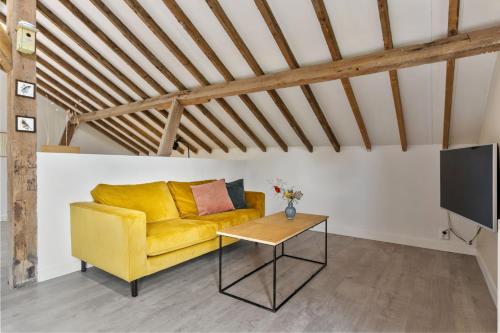 a living room with a yellow couch and a table at Boerderijwoning 't Trogje in Heiloo