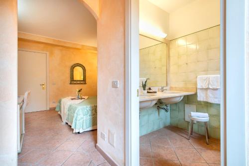 a bathroom with a sink and a bed in a room at Hotel Fertilia in Fertilia