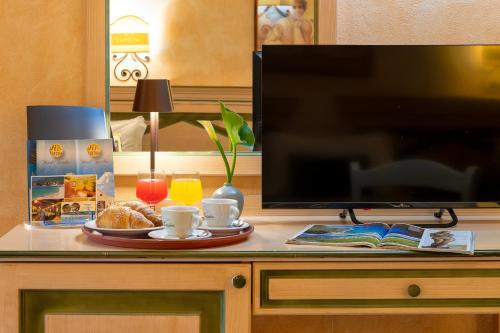 a table with a plate of food and a flat screen tv at Hotel Fertilia in Fertilia