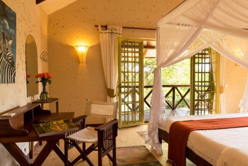 a bedroom with a bed and a table and a desk at Kili Villa Kilimanjaro Luxury Retreat in Arusha