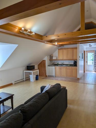 a living room with a couch and a kitchen at Aux petits oiseaux in Baie-Saint-Paul