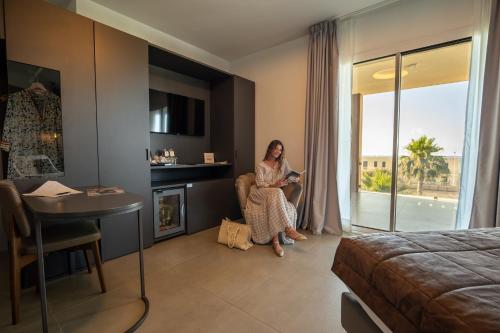 a woman sitting in a chair in a hotel room at Resort La Battigia Beach & Spa in Alcamo Marina