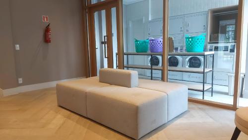 a white ottoman in a living room with a microwave at Novo studio sofisticado ao lado do Allianz Parque in Sao Paulo