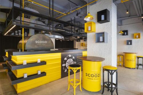a restaurant with a yellow counter and stools at Radisson RED Phuket Patong Beach in Patong Beach