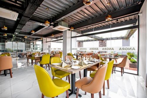 a restaurant with yellow chairs and tables at Royal Mark Hotel in Sylhet