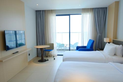 a hotel room with two beds and a television at Modern Beach Apartment - Arena Resort Cam Ranh in Cam Ranh International Airport