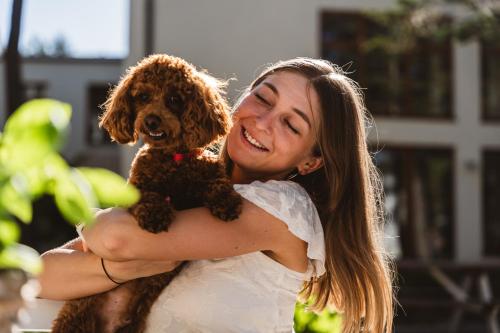 une femme tenant un chien marron dans ses bras dans l'établissement Neptuno Resort & Spa, à Dźwirzyno