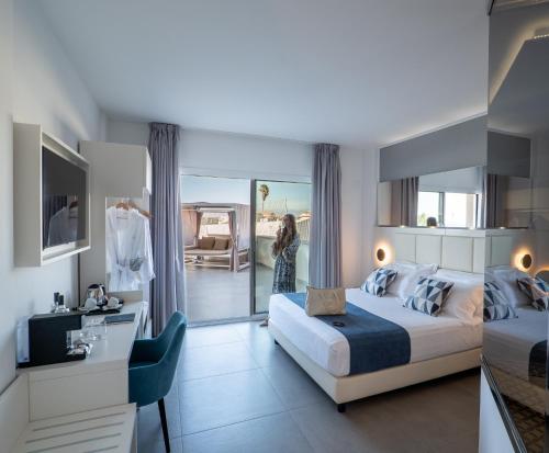 a woman is in a hotel room with a bed at Resort La Battigia Beach & Spa in Alcamo Marina