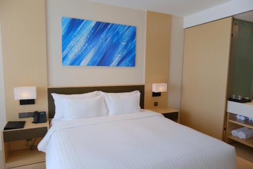a bedroom with a white bed and a blue painting on the wall at Modern Beach Apartment - Arena Resort Cam Ranh in Cam Ranh International Airport