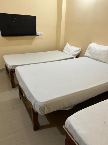 two beds in a room with a tv on the wall at Sri Lingaraja Temple Stay Budget Rooms & Dormitory in Old Town in Bhubaneshwar