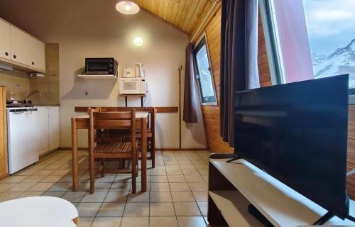 a kitchen with a table and a tv in a room at Depto 5 pax, 2 baños, Cirrus 967 in Las Lenas