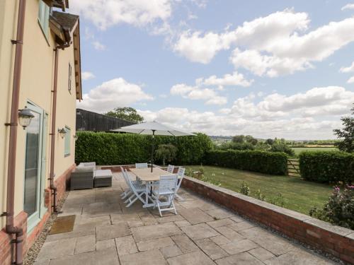 a patio with a table and chairs and an umbrella at Filly Brook in Worcester