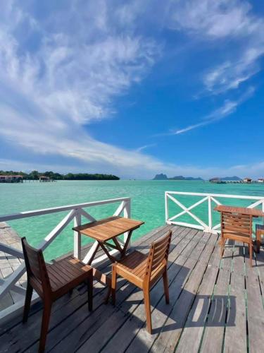two benches and a table on a dock with the water at Seaweed Village Deluxe Room in Semporna