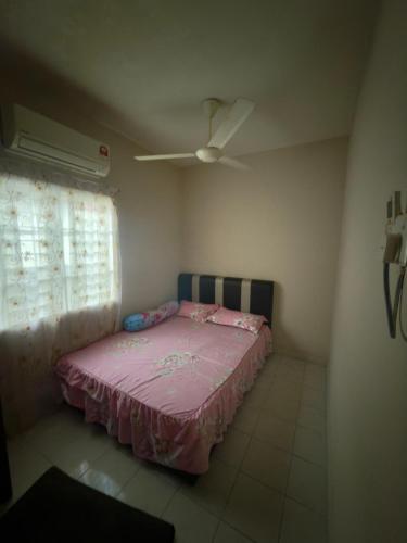 a bedroom with a pink bed and a ceiling fan at Homestay Jawahir in Mentekab