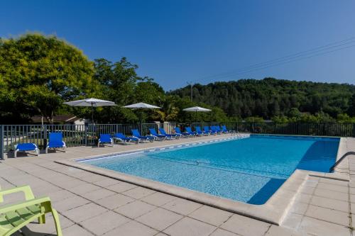 une grande piscine avec des chaises et des parasols bleus dans l'établissement Chalet Franklin 2 personnes, à Saint-Martial-de-Nabirat