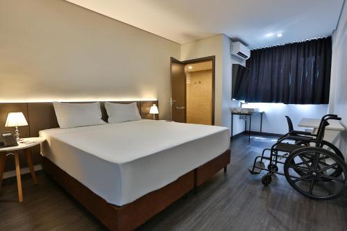 a bedroom with a bed and a wheelchair in it at Executive Inn Fernandopolis in Fernandópolis