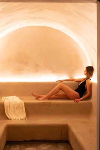 a woman sitting on the edge of a bath tub at L'Hôtel & Spa du Castellet in Le Castellet