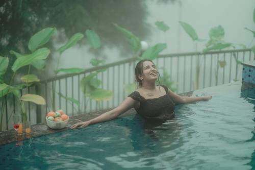 a woman is sitting in a swimming pool at CASA SIGN PRIVATE POOL VILLa in Meppādi