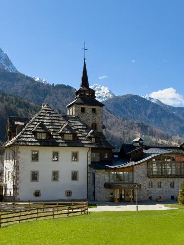 a large building with a tower on top of a field at Hammerack Hotel, SPA & Wellness in Malborghetto Valbruna