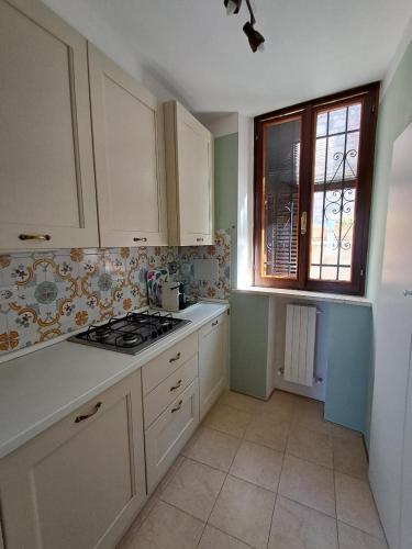 una cucina con armadietti bianchi, piano cottura e finestra di A casatua home ad Assisi