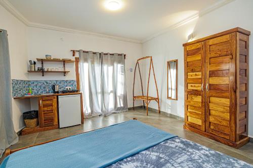 a room with a bed and a dresser and a kitchen at TinJaLa Lodge in Brufut