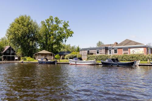 three boats are docked on the water next to houses at Waterherberg It Beaken in Heeg