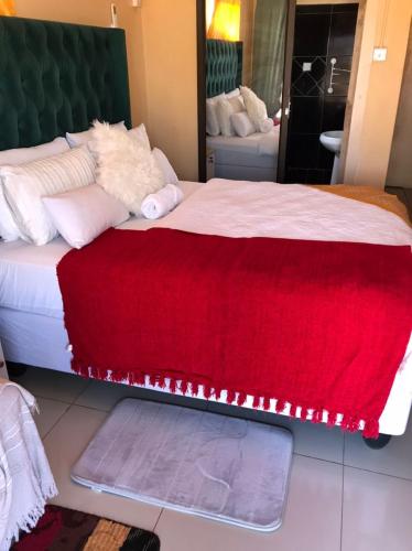 a bedroom with a large bed with a red blanket at Kalahari in Sekoma