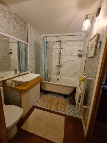 a bathroom with a tub and a toilet and a sink at Maison Maisy in Navarrenx