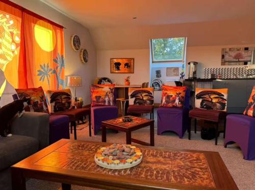 a living room with purple chairs and a cake on a table at Celebrating or Relaxing 5-star farm stay with spa and more! in Kirk of Shotts