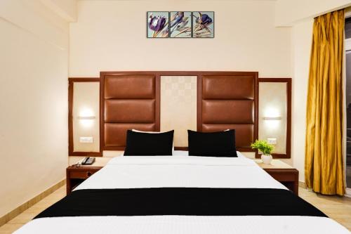 a bedroom with a large bed with a wooden headboard at Super Townhouse Oak Silver City Chowk Formerly HW Residency in Dehradun