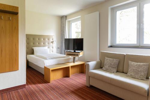 a bedroom with a bed and a couch and a tv at Hotel An der Gruga in Essen
