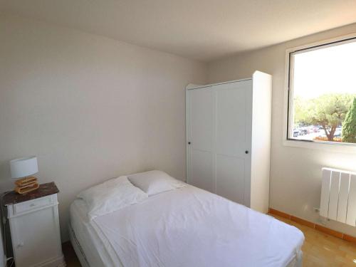 une chambre avec un lit blanc et une fenêtre dans l'établissement Appartement 2P Cabine proche plage avec garage, lumineux et bien situé au Grau-du-Roi - FR-1-307-136, au Grau-du-Roi