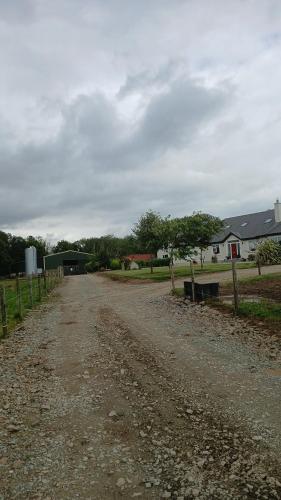 a dirt road with a fence and a house at Modern Countryside apartment Killmallock Lodge in Enniscorthy