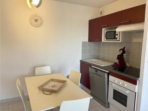 une cuisine avec une table, des chaises et une horloge murale dans l'établissement Appartement 2 pièces avec terrasse et parking privé, proche centre et plage - FR-1-229D-131, à Fleury