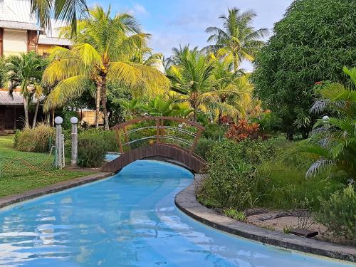 a bridge over a pool in a yard with palm trees at CosyNest Apartment in Cap Malheureux