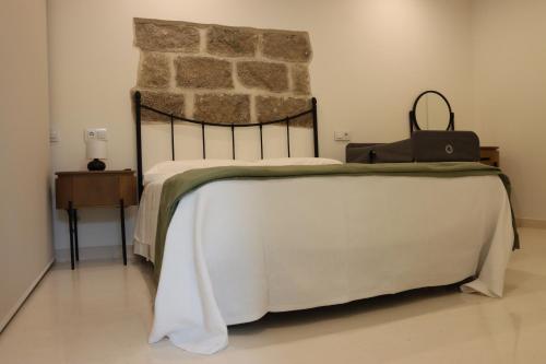 ein Schlafzimmer mit einem Bett mit einer Steinwand in der Unterkunft Casa Rural La Tajuela in Bohonal de Ibor