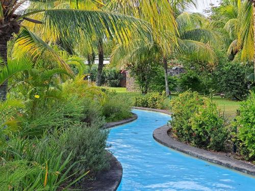 a swimming pool in a garden with palm trees at CosyNest Apartment in Cap Malheureux