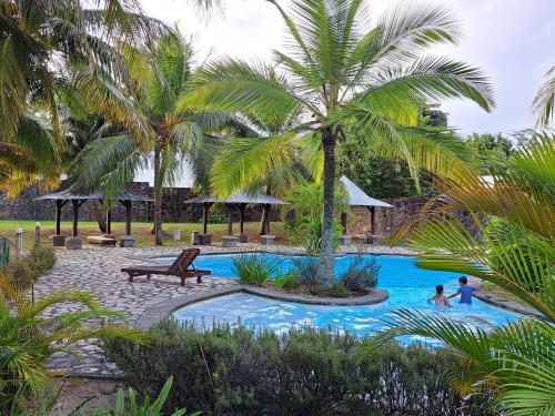 a pool with palm trees and people playing in it at CosyNest Apartment in Cap Malheureux